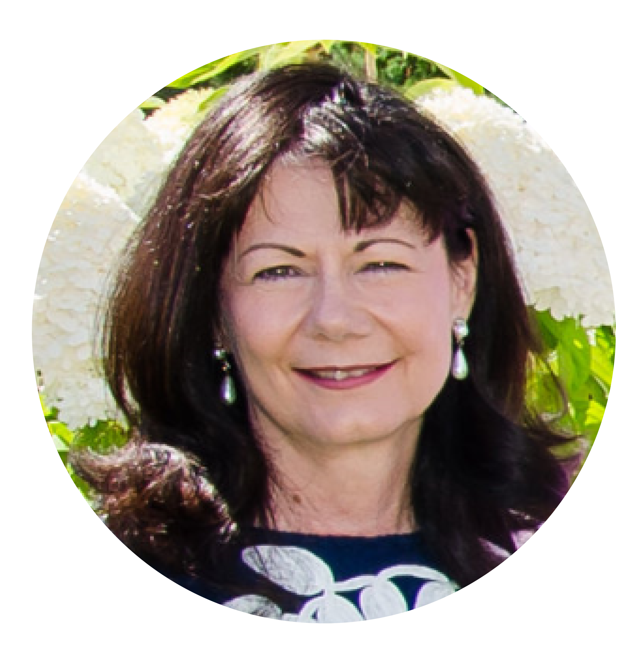 Woman with medium length brown hair and bangs and white earrings