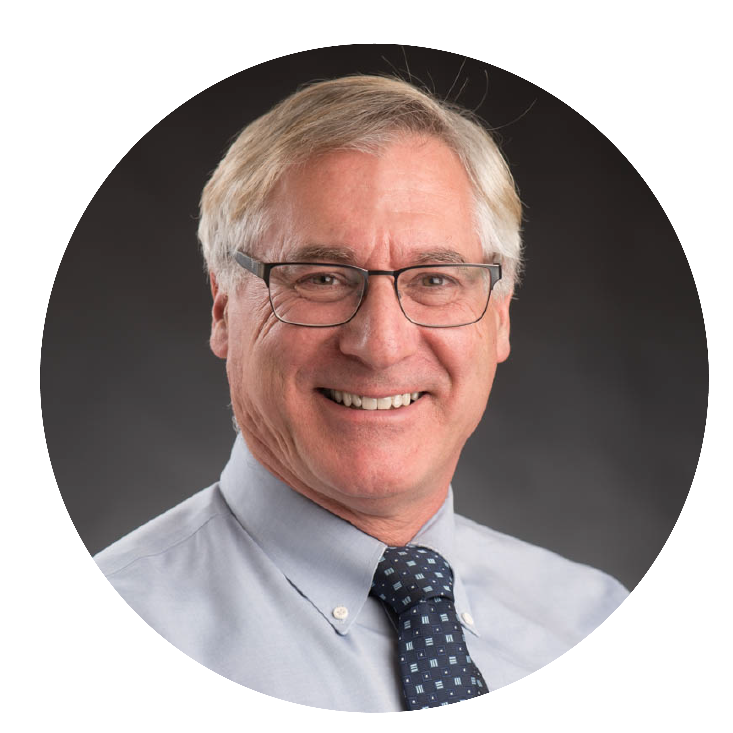 Midlife grey haired man in pale shirt and dark tie and glasses, smiling