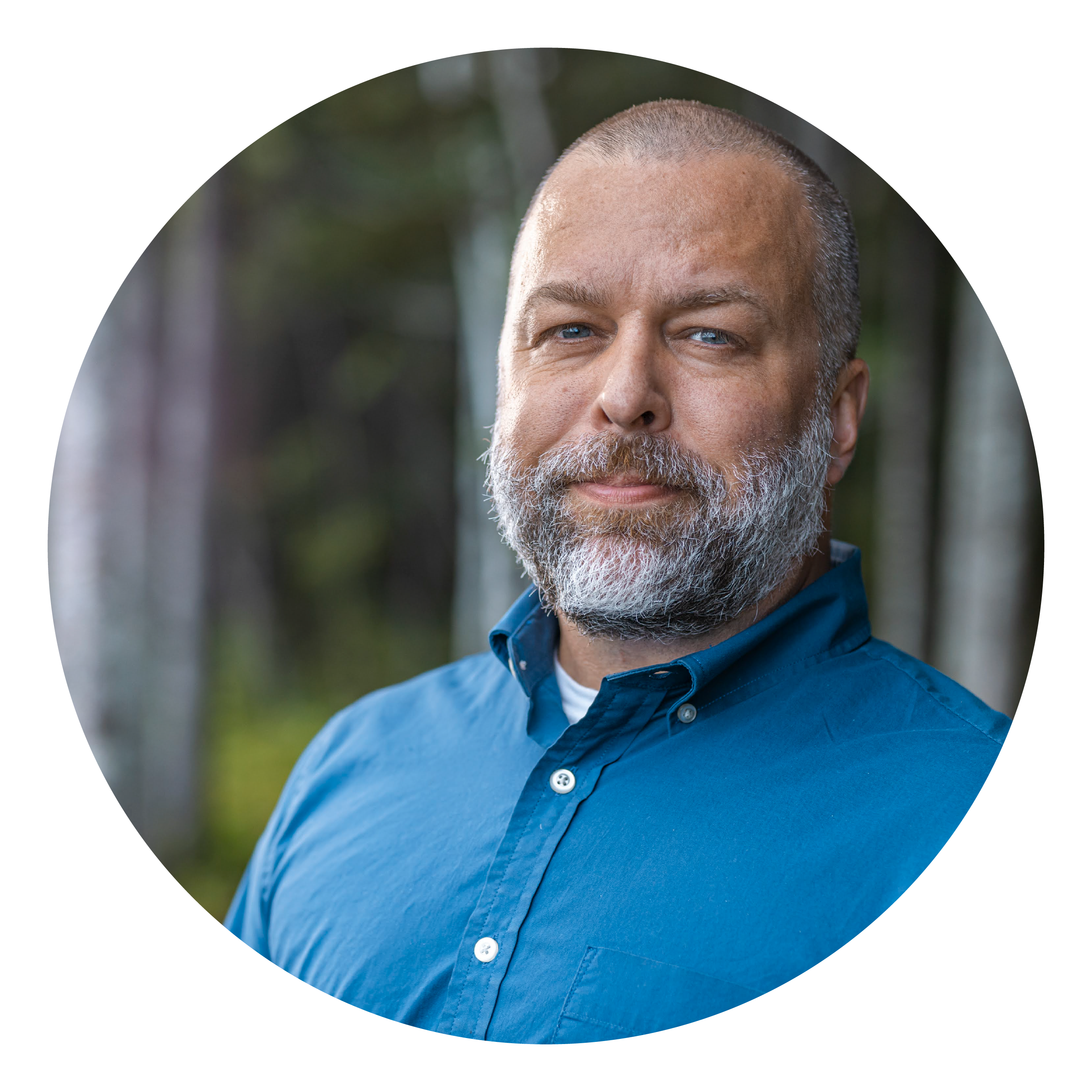 A man with a grey beard and blue eyes and shirt 