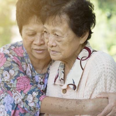 Senior woman hugging her family member in the park during a sunny day.