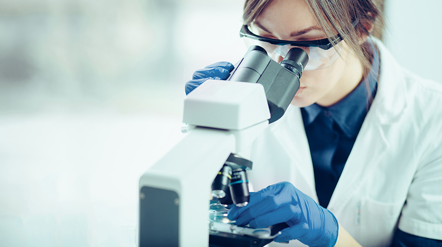 Female scientist investigating something using her microscope.