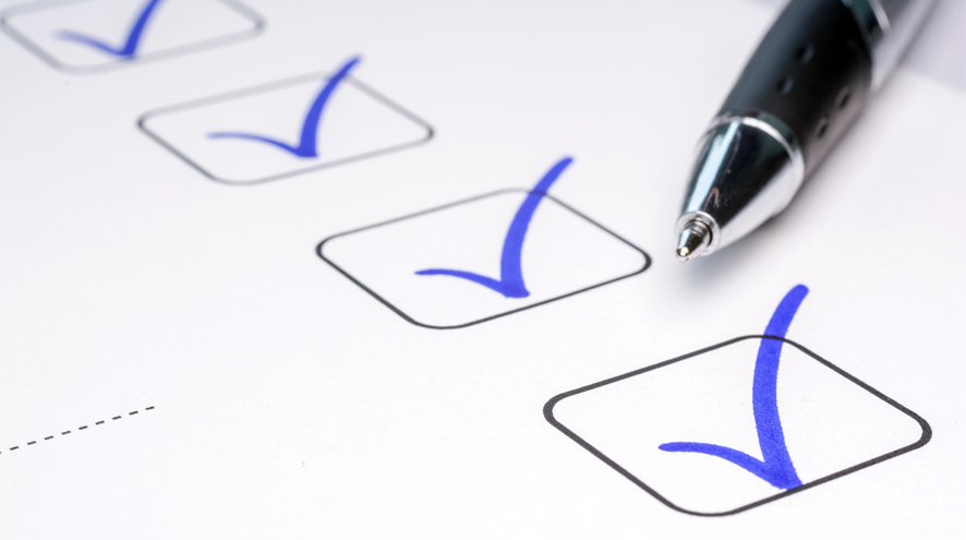 A pen rests on a piece of paper containing a line of blue checkmarks