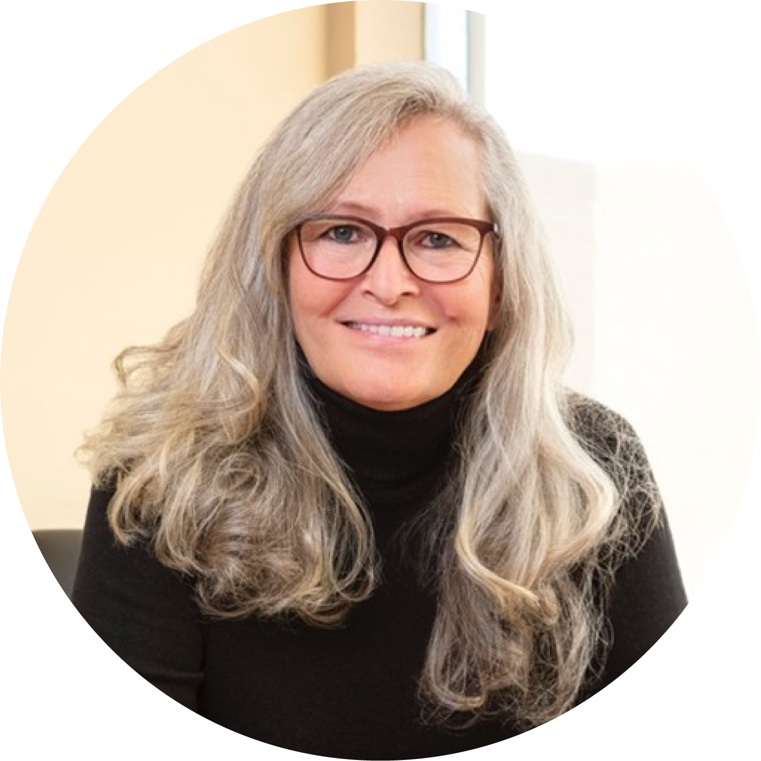 Woman with long silver hair, brown glasses and black turtleneck