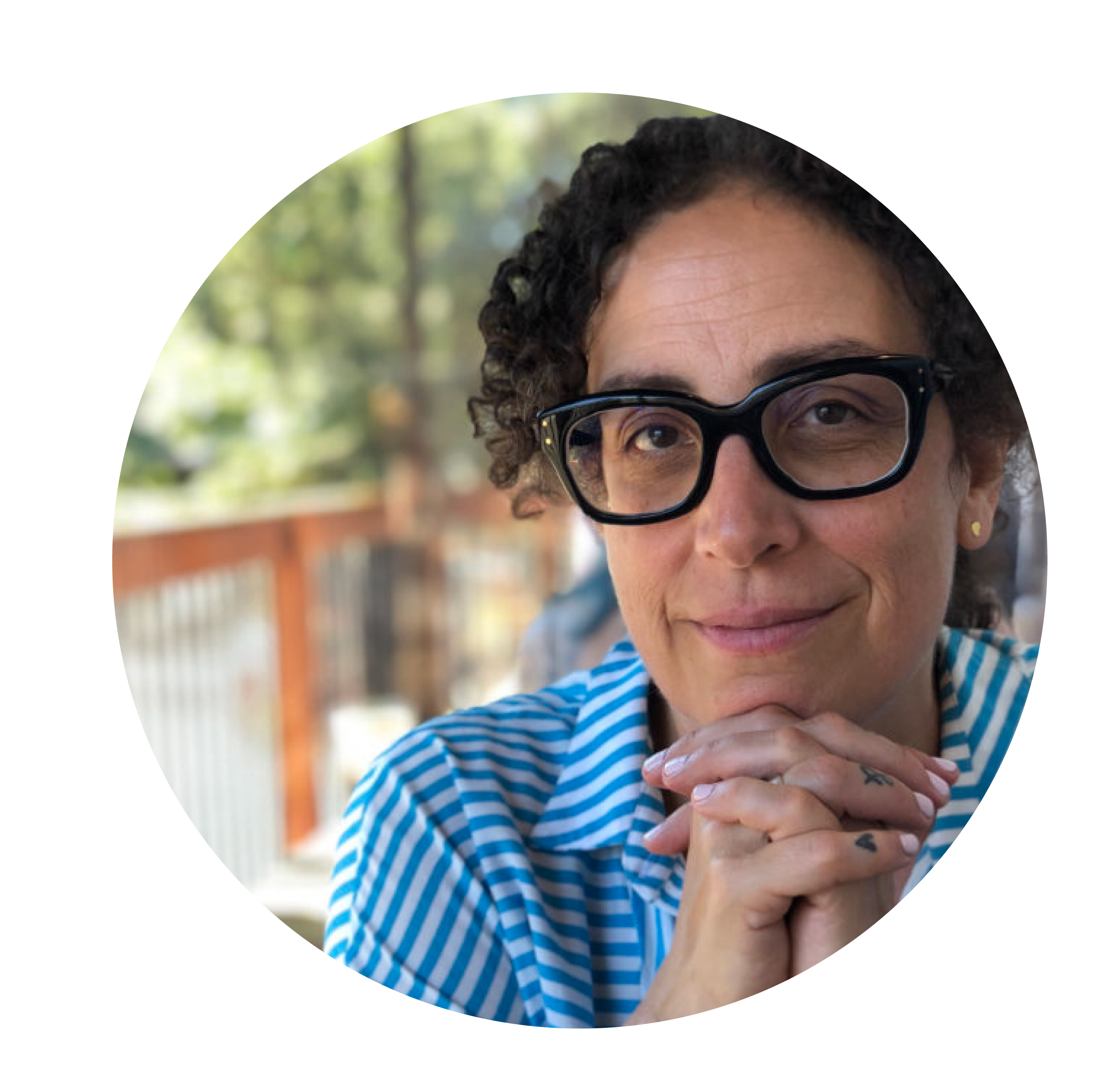 Woman with curly brown hair, striped blue shirt and black glasses