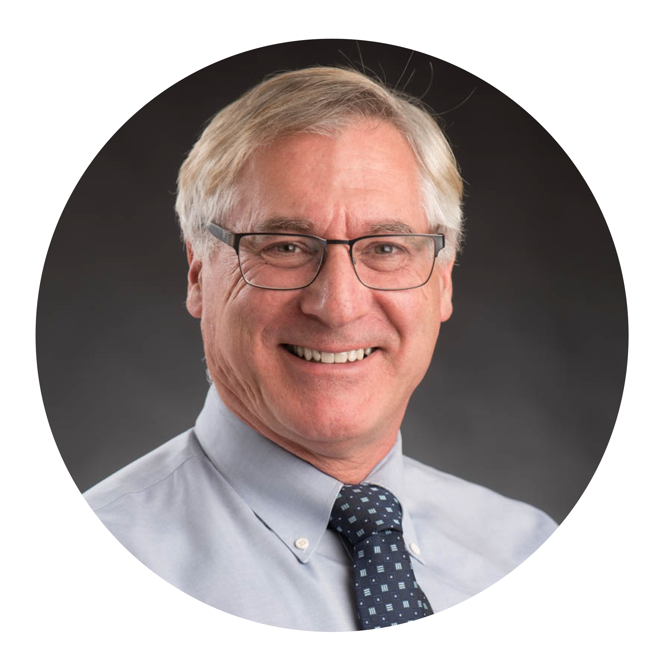 Midlife grey haired man in pale shirt and dark tie and glasses, smiling