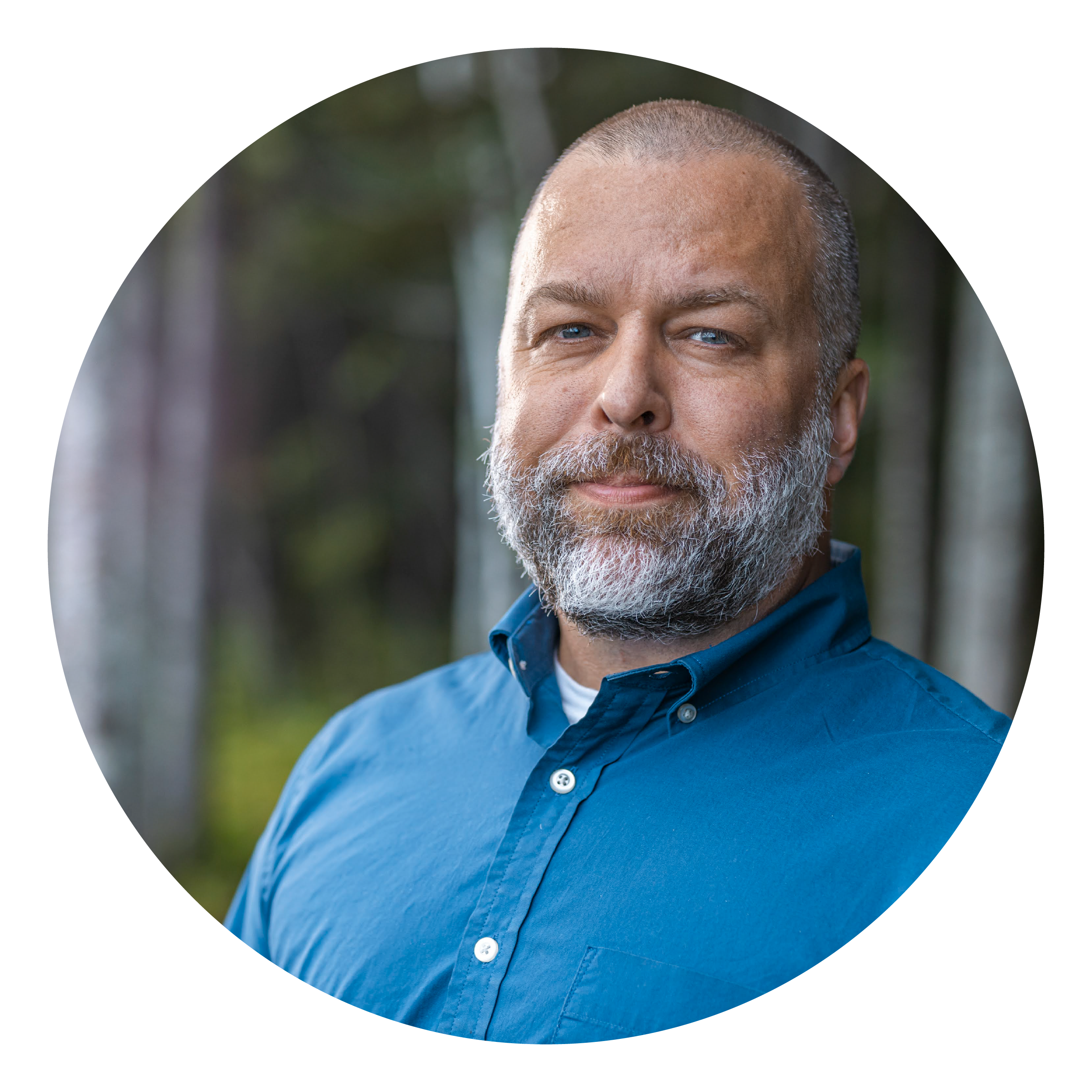 A man with a grey beard and blue eyes and shirt 