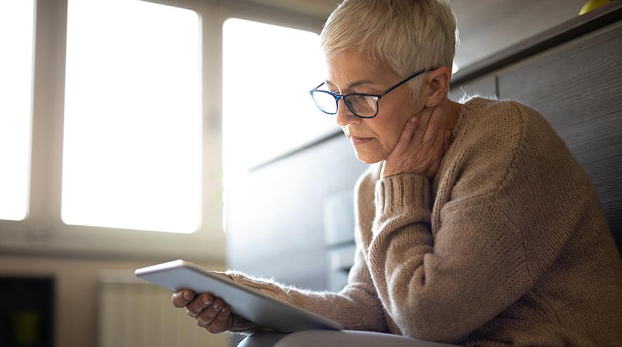 Senior woman reading on tablet.