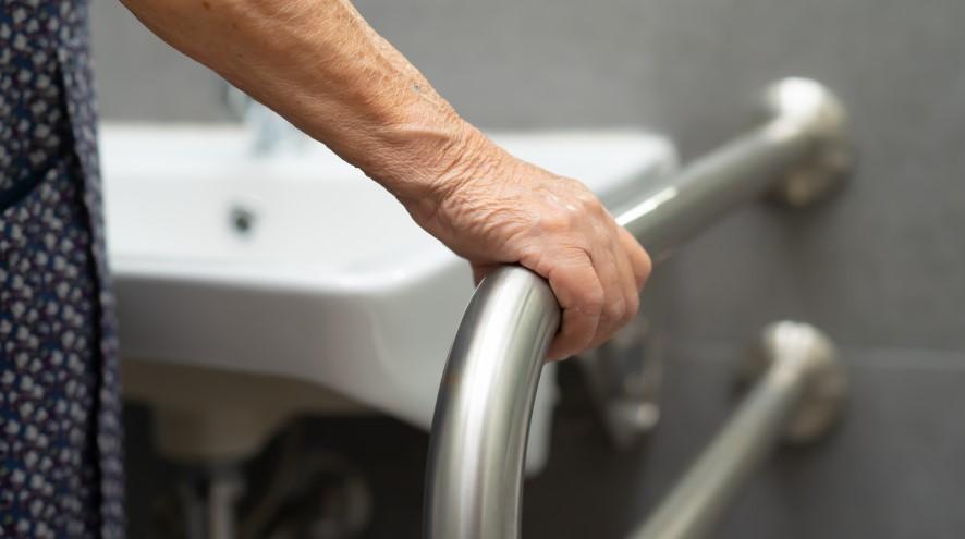 Senior holding the handrail in a bathroom.