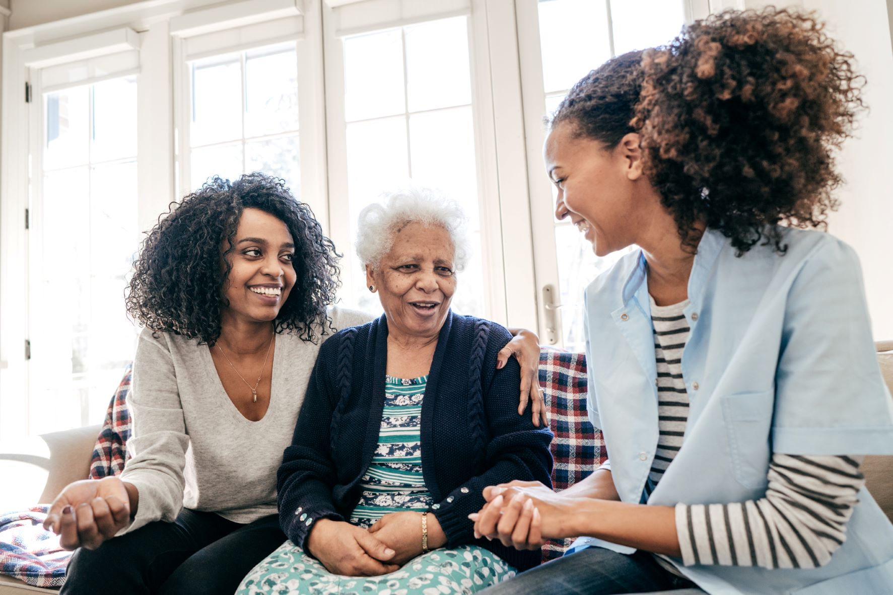 Younger woman with arm around older woman speak to caregiver