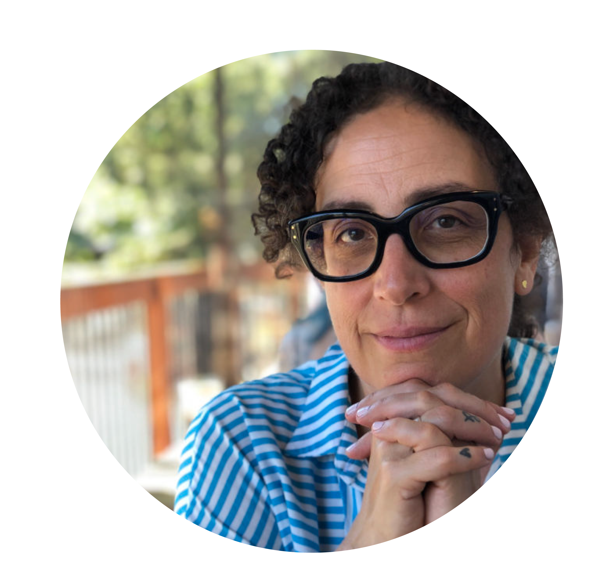 Woman with curly brown hair, striped blue shirt and black glasses