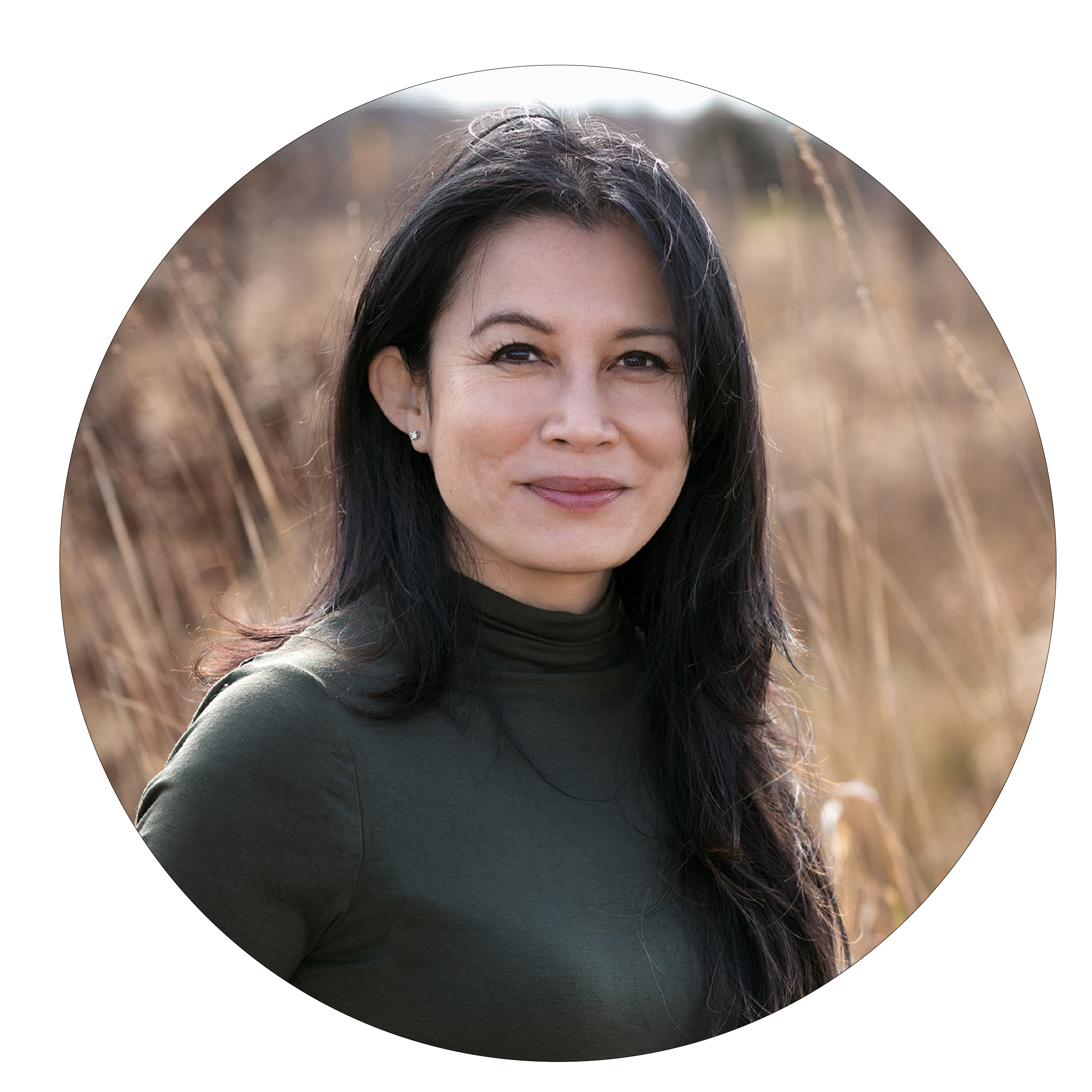 Woman with long black hair and green shirt smiling outdoors