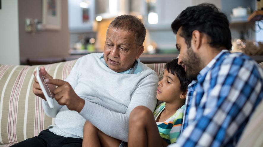 A senior man showing a boy and young man information on a tablet