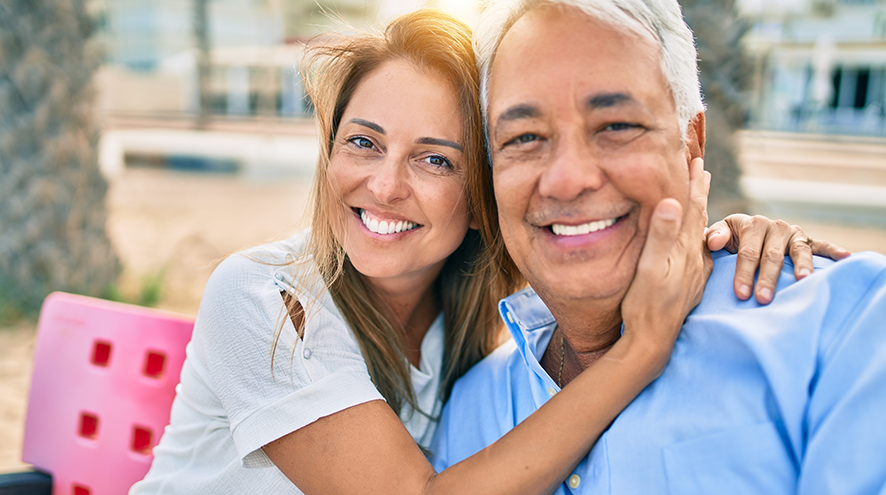 Middle-aged couple smiling on a pink bench.