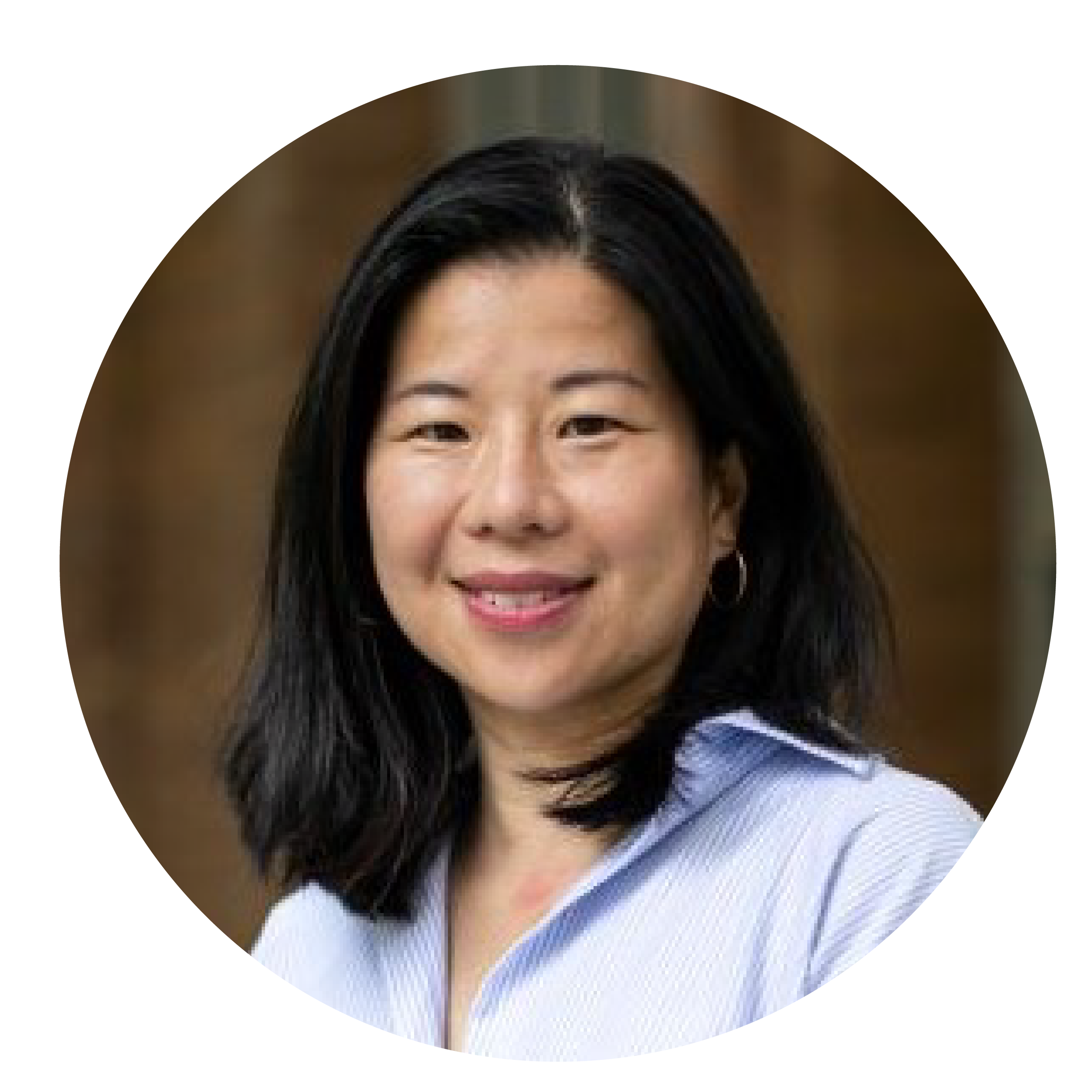 A woman with midlength black hair, smiling in a blue shirt