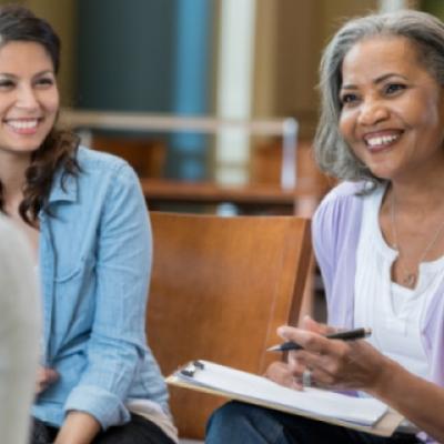 Smiling woman wearing purple with a clipboard at a support group 