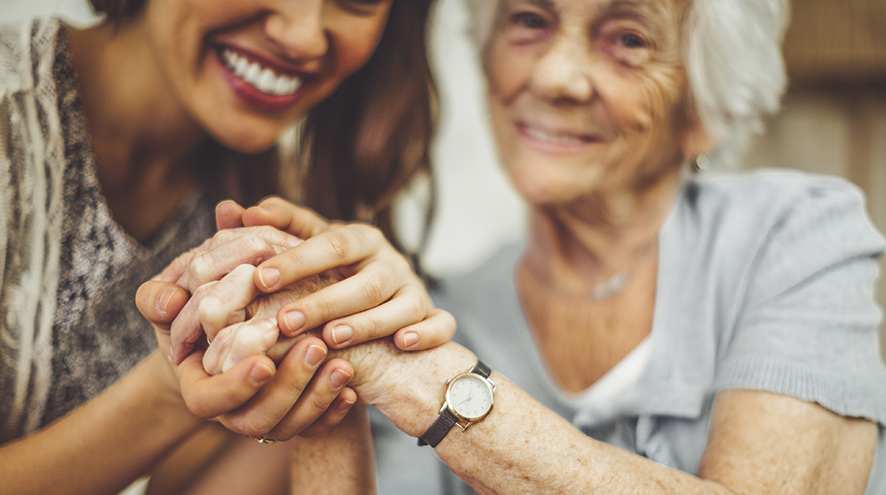 Care worker and senior woman holding hands.