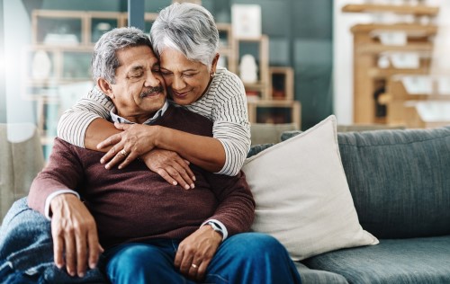 Senior woman hugging her husband. Both are smiling.